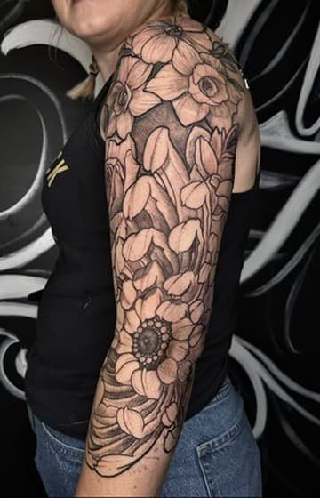 Fine line floral sleeve tattoo — delicate botanical linework with chrysanthemums and flowing organic shapes wrapping the forearm